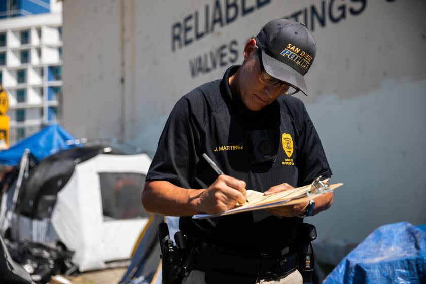 San Diego, CA - April 25: San Diego Police Officers Jeff Martinez -a member of SDPD's Homeless Outreach Team - writes a reduced-cost voucher for homeless resident looking to get a California ID card in downtown on Monday, April 25, 2022 in San Diego, CA. The team interacts with homeless residents and provide direction to local service providers. (Adriana Heldiz / The San Diego Union-Tribune)