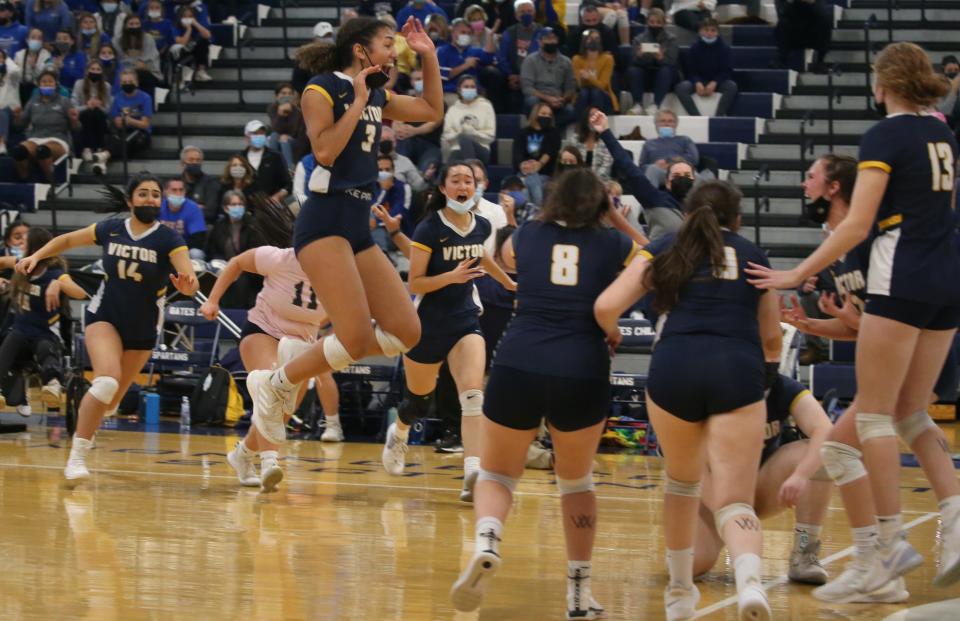 Victor's Alex McKenzie (3), center, leaps into her teammates as they celebrate their win over Penfield in their Section V Class AA championship finals match up Saturday, Nov. 6, 2021 at Gates Chili High School.  Victor won the close contest in five sets; 18-25, 25-23, 25-20, 20-25 and 27-25. 