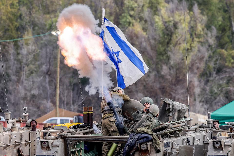 Israeli soldiers cover their ears as they fire mortar rounds from an armored vehicle at a position along the border in southern Israel on Jan. 3, 2024, amid the ongoing conflict between Israel and the Palestinian militant group Hamas.