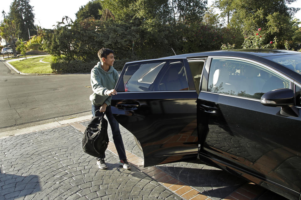 In this photo taken Tuesday, Oct. 29, 2019, Saahas Kohli, 14, exits a Zum ride share vehicle at his home in Saratoga, Calif. A handful of ride-hailing companies have surfaced that allow parents to order rides, and in some cases childcare, for children using smartphone apps. The promise is alluring at a time when children are expected to accomplish a dizzying array of extracurricular activities and the boundaries between work and home have blurred. But the companies face hurdles convincing parents that a stranger hired by a ride-hailing company is trustworthy enough to ferry their most precious passengers. (AP Photo/Ben Margot)