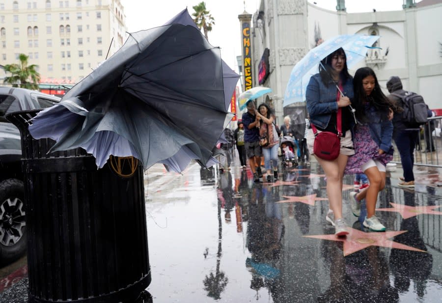 A broken umbrella protrudes from a trash barrel as pedestrians walk down Hollywood Boulevard during Tropical Storm Hilary, Sunday, Aug. 20, 2023, in Los Angeles. (AP Photo/Chris Pizzello)