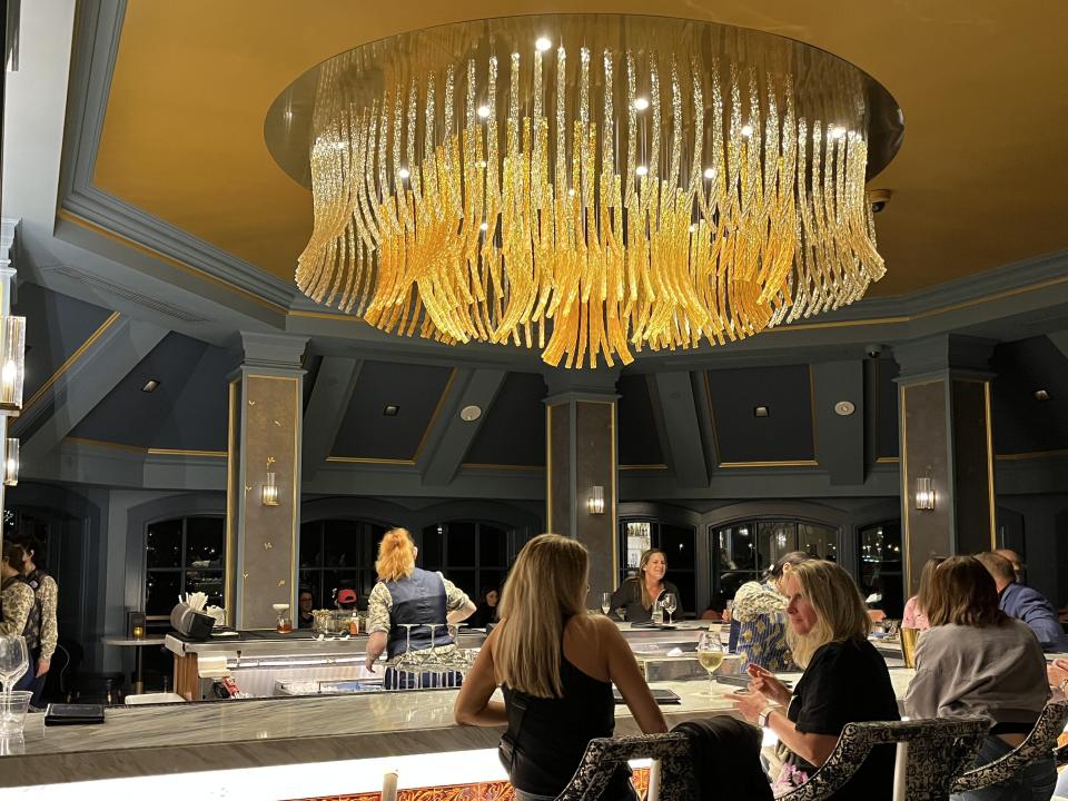 The bar room with a large, golden chandelier hanging from the ceiling.
