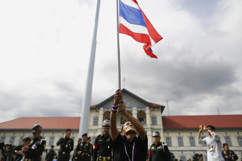 An anti-government protester waves a national flag after breaking into the compound of the Royal Thai Army headquarters in Bangkok