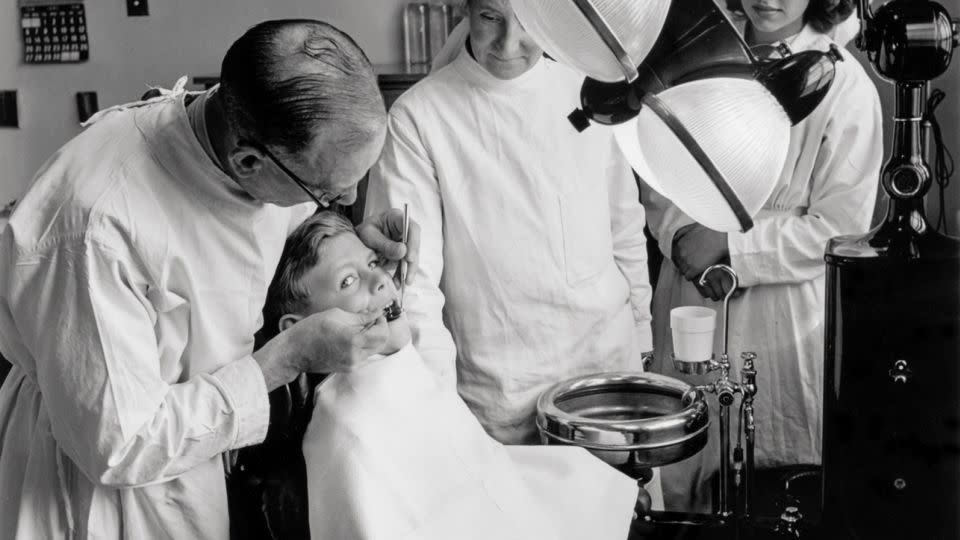 A dentist with his young patient at a health center surgery in Bristol shortly after the NHS was established in July 1948. - Popperfoto/Getty Images