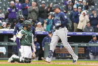 Seattle Mariners' Cal Raleigh, right, crosses home plate after hitting a solo home run as Colorado Rockies catcher Elias Díaz looks on in the second inning of a baseball game Saturday, April 20, 2024, in Denver. (AP Photo/David Zalubowski)