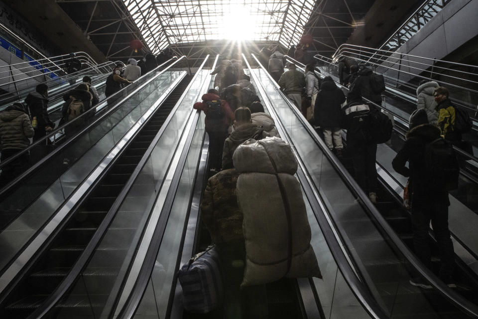 Un trabajador migrante lleva dos bolsas pesadas con sus pertenencias en una estación de tren de Pekín, el 18 de enero de 2023. (Gilles Sabrie/The New York Times).