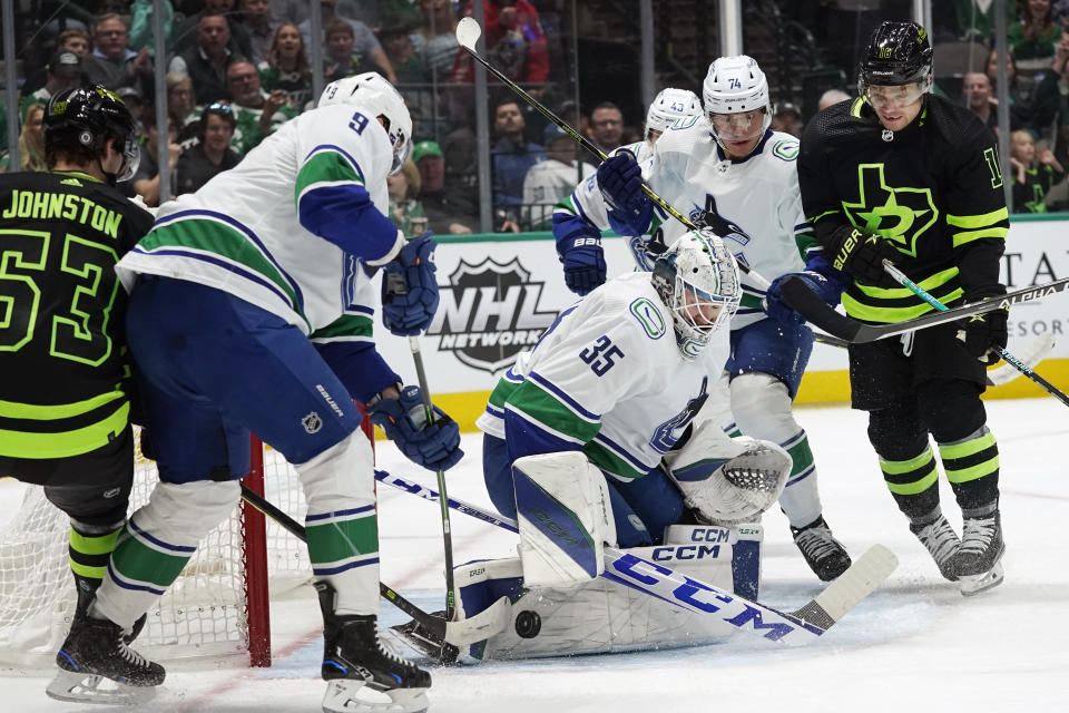 Vancouver Canucks, including Thatcher Demko (35), J.T. Miller (9) and Ethan Bear (74) play against the attack by Dallas Stars centers Max Domi (18) and Wyatt Johnston (53) during the first period of an NHL hockey game in Dallas, Saturday, March 25, 2023. (AP Photo/LM Otero)