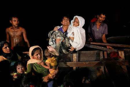 A man lifts an elderly woman from the boat as hundreds of Rohingya refugees arrive under the cover of darkness from Myanmar to the shore of Shah Porir Dwip, in Teknaf, near Cox's Bazar in Bangladesh, September 27, 2017. Picture taken September 27, 2017. REUTERS/Damir Sagolj
