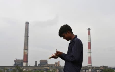 A boy examines a pigeon on a rooftop near a coal-fired power plant in New Delhi, India, July 20, 2017. REUTERS/Adnan Abidi