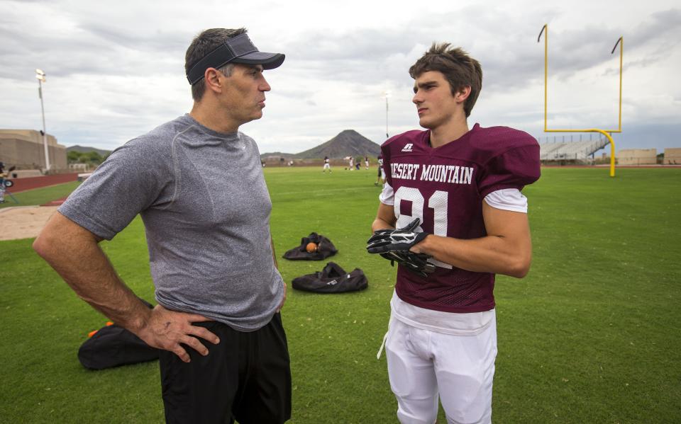 Kurt Warner, assistant coach for quarterbacks and receivers at Desert Mountain High School, talks with his son Kade, a sophomore receiver, at the start of practice on Sept. 9, 2014.