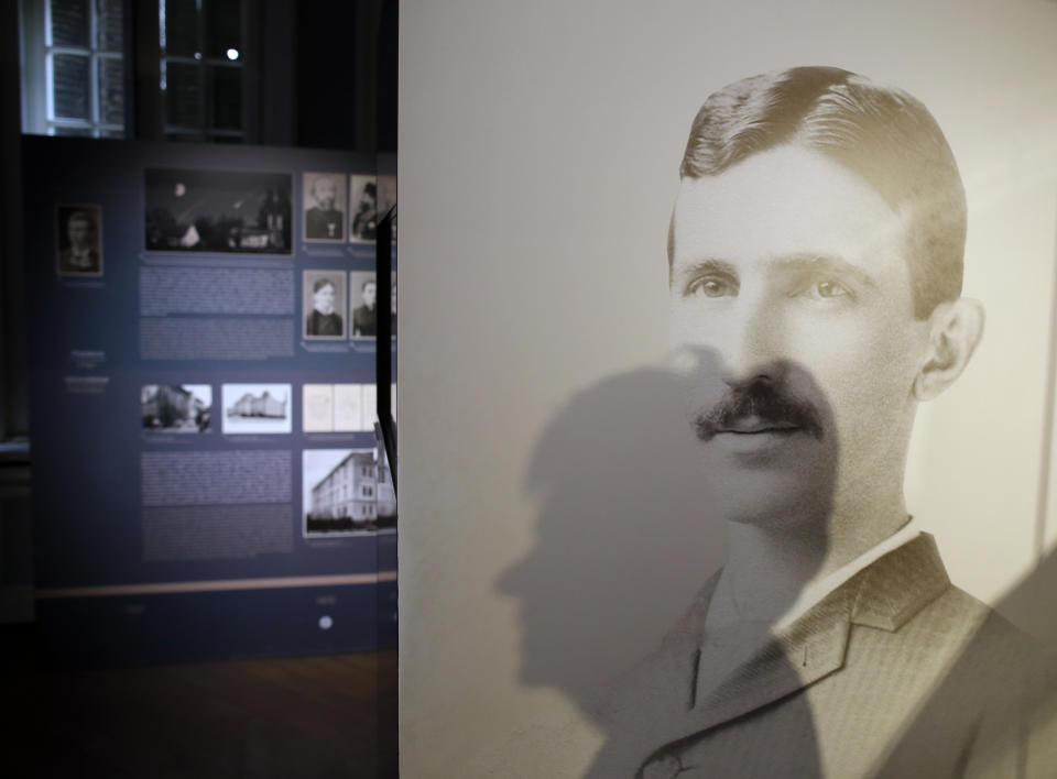In this Thursday, March 7, 2019 file photo, a shadow of Milica Kesler, curator and archivist is cast onto a poster of Nikola Tesla at the Nikola Tesla museum in Belgrade, Serbia. (AP Photo/Darko Vojinovic)