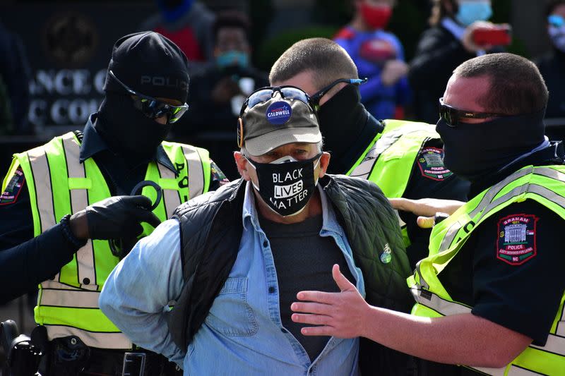 A man is detained by Graham Police officers after a moment of silence during a Get Out The Vote march in Graham