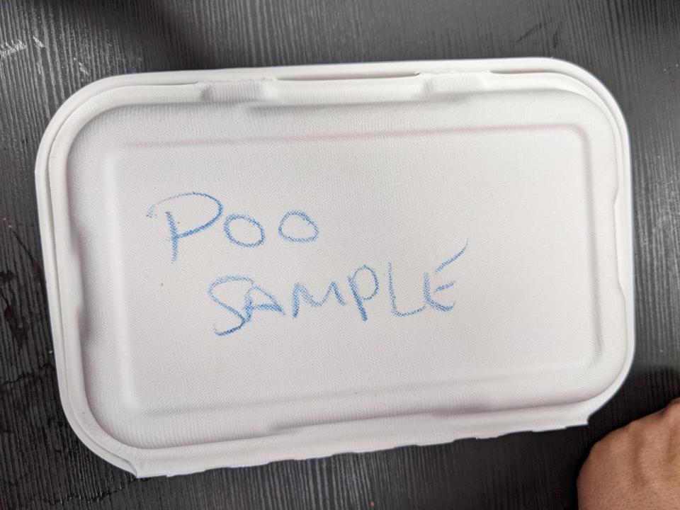 A takeout box containing my leftover onion rings, with "poo sample" scrawled on it