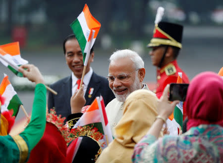 Indian Prime Minister Narendra Modi (R) is greeted by the children in traditional costumes as Indonesia President Joko Widodo (L) looks on at the presidential palace in Jakarta, Indonesia May 30, 2018. REUTERS/Darren Whiteside