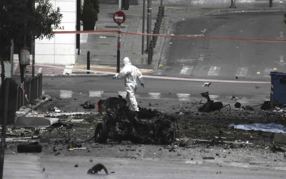 Police bomb disposal experts search for evidence next to remains of a car after a car bomb explosion in central Athens on Thursday, April 10, 2014. A bomb exploded outside a Bank of Greece building in central Athens before dawn Thursday, causing some damage but no injuries. The blast came hours before Greece was to return to the international bond markets for the first time in four years, and a day before German Chancellor Angela Merkel was to visit Athens.(AP Photo/Dimitri Messinis)