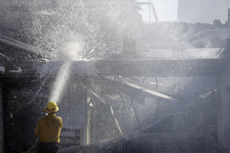 A firefighter tries to put out a residence fire caused by a wildfire Friday, Oct. 25, 2019, in Santa Clarita, Calif. An estimated 50,000 people were under evacuation orders in the Santa Clarita area north of Los Angeles as hot, dry Santa Ana winds howling at up to 50 mph (80 kph) drove the flames into neighborhoods(AP Photo/Marcio Jose Sanchez)
