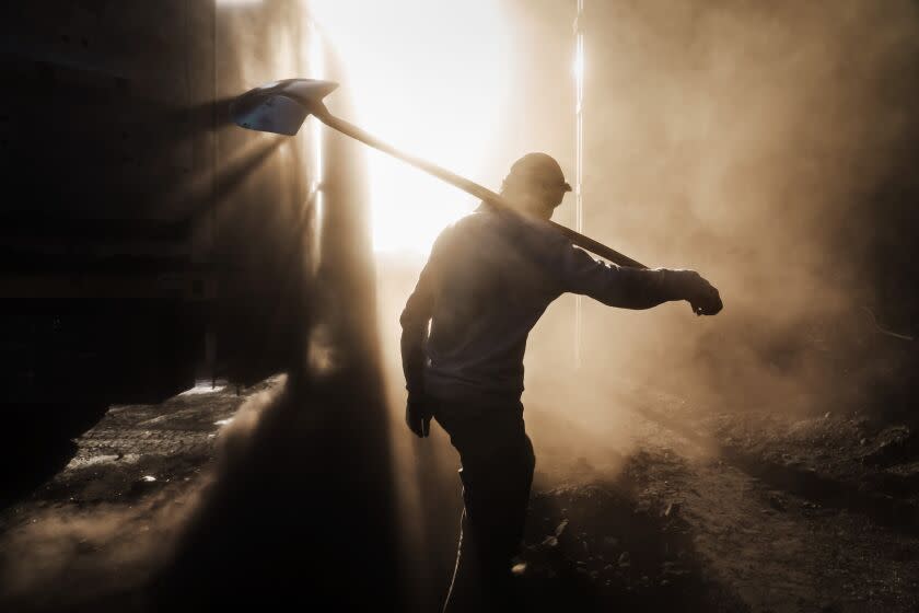 KABUL, AFGHANISTAN -- SEPTEMBER 8, 2022: Fazelmenallah Yazdanpanah, 27, from Bamiyan province, walk through the dust to shovel coal all day, alongside other men, earning them about 200-300 Afghanis each per day, which is equivalent to a few dollars, in the Deh Sabz District near Kabul, Afghanistan, Thursday, Sept. 8, 2022. The new Taliban regime has been focusing on streamlining transport, said David Mansfield, an expert on AfghanistanOs economy. It has channeled trade to formal border crossings, tightened security along the border to reduce smuggling and reduced checkpoints. Mansfield said the regime has also doubled coal exports to Pakistan this year compared with the year before, taking advantage of a spike in prices because of the war in Ukraine. (MARCUS YAM / LOS ANGELES TIMES)