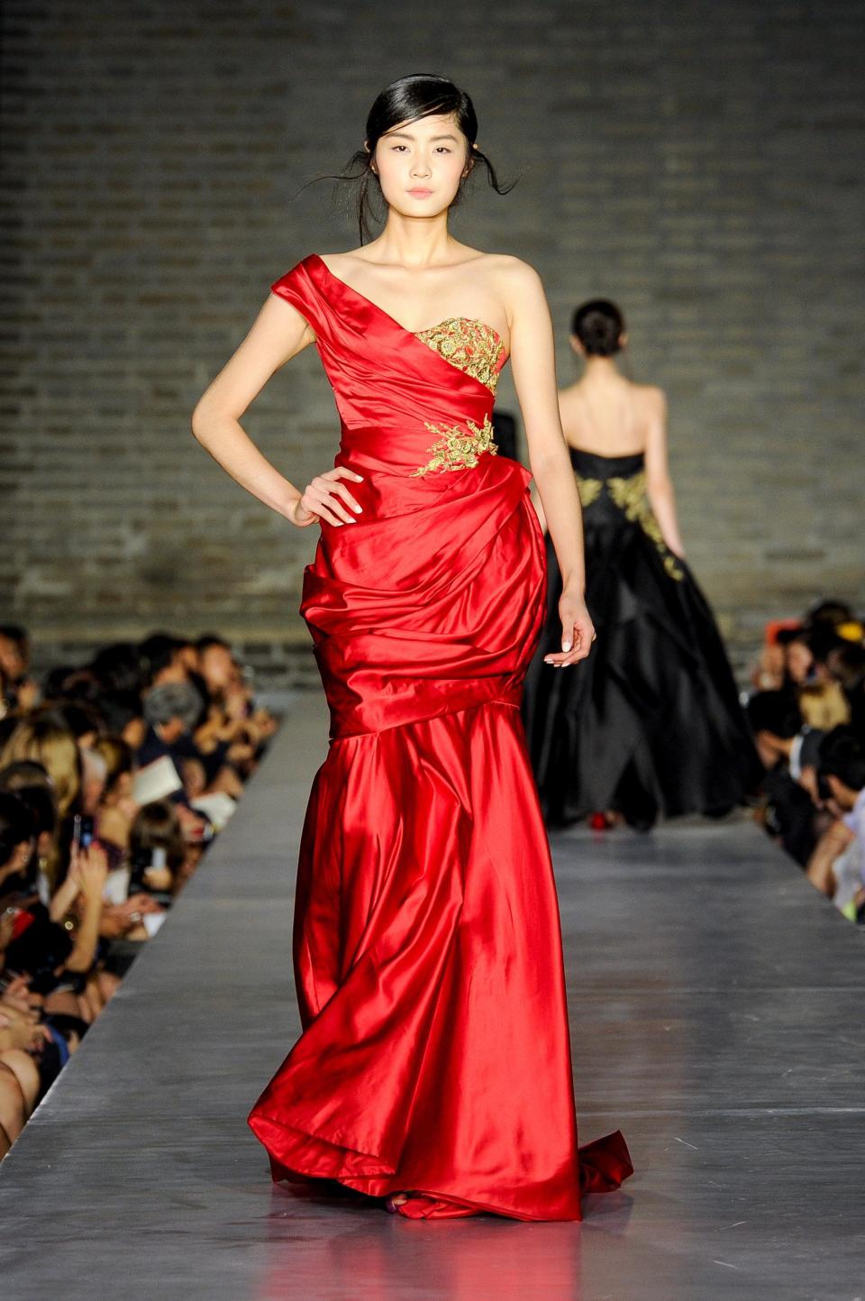 This June 2013 photo released by the Council of Fashion Designers of America (CFDA) shows a model wearing a red Marchesa gown with gold embroidery during a fashion show by New York-based designers in Beijing, China. Rag & Bone, Marchesa and Proenza Schouler, among the top in their class of cool, youngish New York-based fashion houses, took a field trip to China recently to introduce themselves to Chinese consumers and to bring home a better understanding of their needs. (AP Photo/Council of Fashion Designers of America, Neil Rasmus)