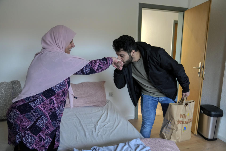 Jihad Ammuri, a 20-year-old Palestinian asylum seeker, kisses his mother's hand after returning to the refugee shelter, in Eichsfeld, Germany, Wednesday, April 24, 2024. Across Germany, cities and counties are introducing new payment cards for asylum-seekers. The new rule, which was passed by parliament last month, calls for the migrants to receive their benefits on a card that can be used for payments in local shops and services. (AP Photo/Ebrahim Noroozi)