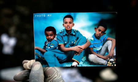 A rescue worker holds a photograph of children suspected to be missing at a pile of garbage following a landslide when a mound of trash collapsed on an informal settlement at the Koshe garbage dump in Ethiopia's capital Addis Ababa, March 13, 2017. REUTERS/Tiksa Negeri