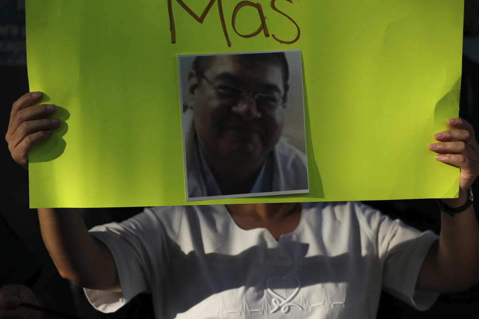 A nurse holds a poster with the image of a doctor who died of COVID-19, outside a public hospital to protest their lack of protective gear, in Mexico City, Tuesday, April 21, 2020. The government has extended its social distancing measures through the end of May, predicting that the cases of the new coronavirus will peak in Mexico in about three weeks. (AP Photo/Fernando Llano)