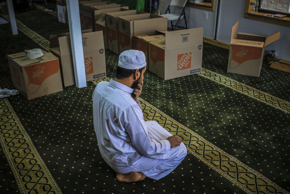 In this Wednesday, April 22, 2020, photo, Imam Mufti Mohammed Ismail, leader of An-Noor Cultural Center and masjid that serves a mostly Bangladeshi Muslim community in the Elmhurst neighborhood in the Queens borough of New York, prays near boxes of food supplies prepared for distribution to those impacted by COVID-19 restrictions. Ismaill says this gives the center the opportunity to fulfill one of Ramadan's tenets — to serve those less fortunate, regardless of religion. (AP Photo/Bebeto Matthews)