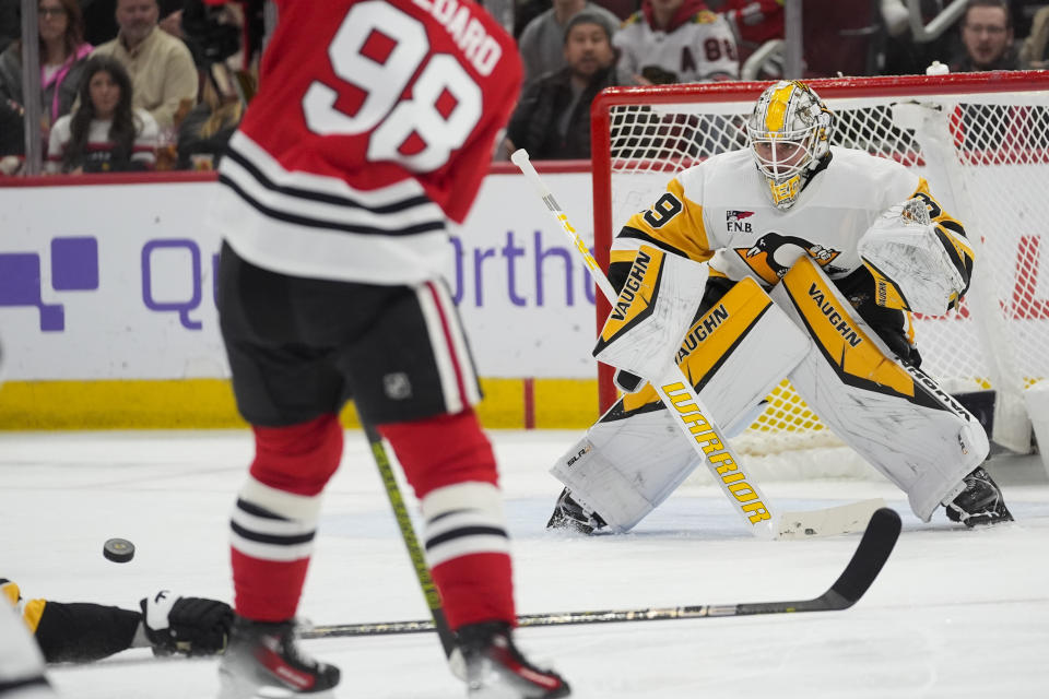 Chicago Blackhawks center Connor Bedard, front, passes the puck to center Philipp Kurashev, who scored on Pittsburgh Penguins goaltender Alex Nedeljkovic during the second period of an NHL hockey game, Thursday, Feb. 15, 2024, in Chicago. (AP Photo/Erin Hooley)