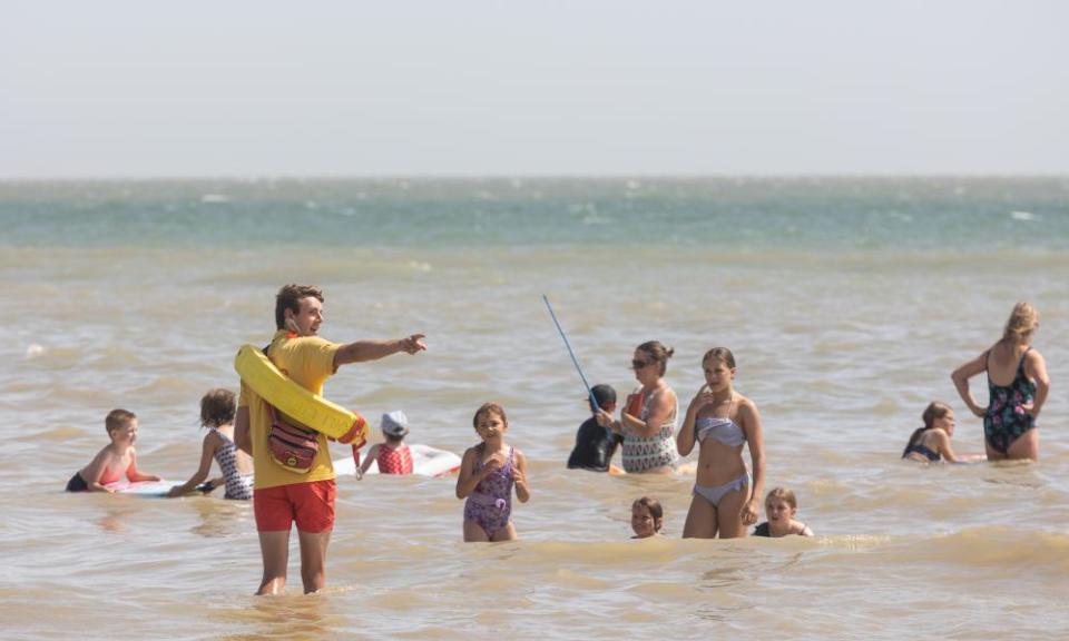 Lifeguard Sam Anderson shows bathers where it is safer to swim.