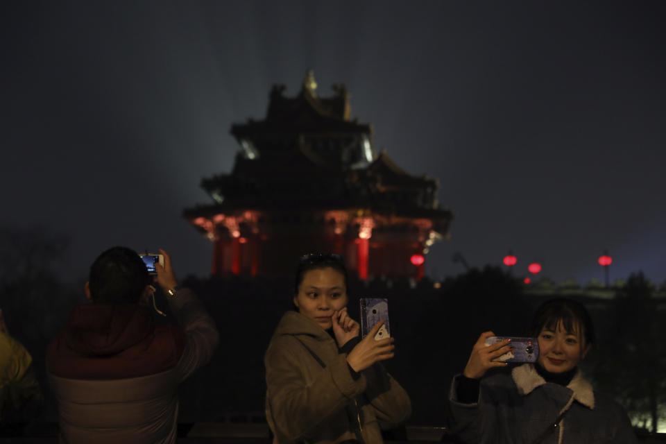 In this Feb. 19, 2019, photo, visitors pose for selfies outside the Forbidden City to catch a glimpse of the evening lights in Beijing. China lit up the Forbidden City on Tuesday night, marking the end of 15 days of lunar new year celebrations. It was not a Lantern Festival the last emperor, who abdicated in 1912, would have recognized. There were lanterns, but those lucky enough to snag tickets saw a laser light show and historic buildings bathed in colorful lights. Others watched from outside the vast walled compound in Beijing, from where Ming and Qing dynasty emperors ruled for five centuries. (AP Photo/Ng Han Guan)