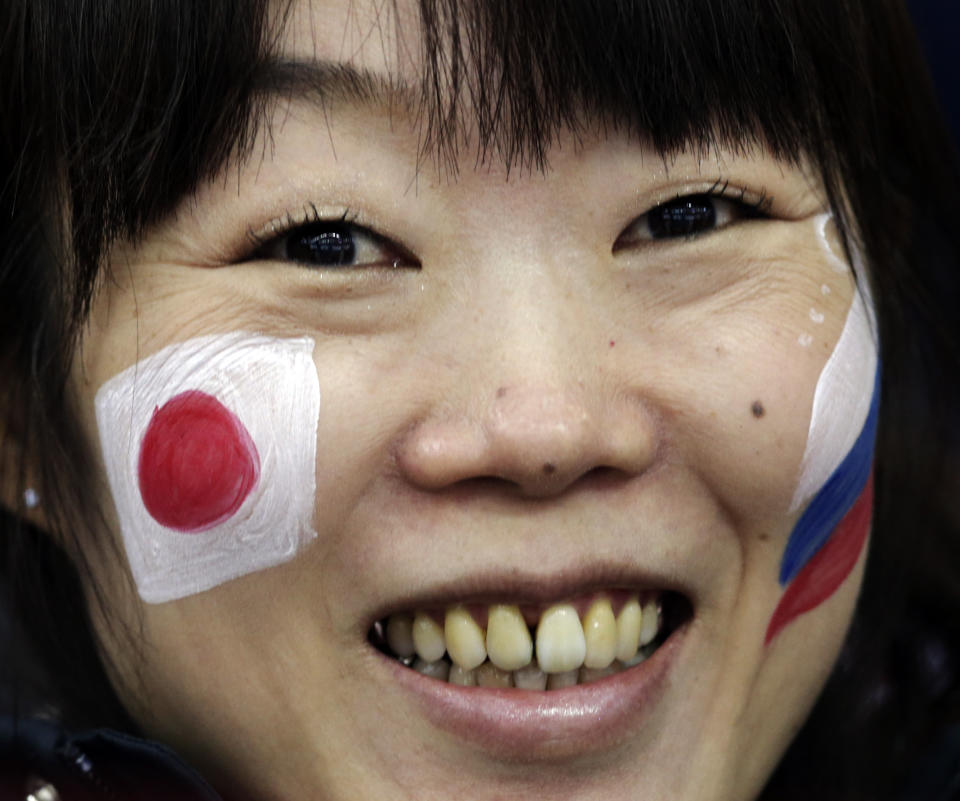 A skating fan, with the Russian and Japanese flags painted on her face, watches the men's 500-meter speedskating race at the Adler Arena Skating Center at the 2014 Winter Olympics, Monday, Feb. 10, 2014, in Sochi, Russia. (AP Photo/Matt Dunham)