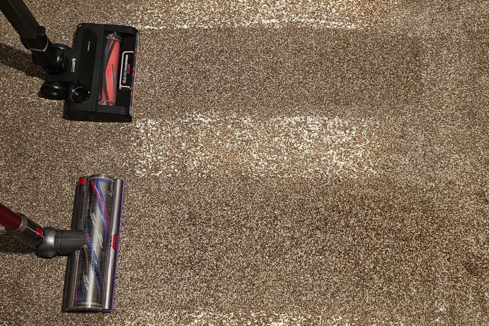Dyson vs Shark vacuums in use cleaning carpeting during testing.
