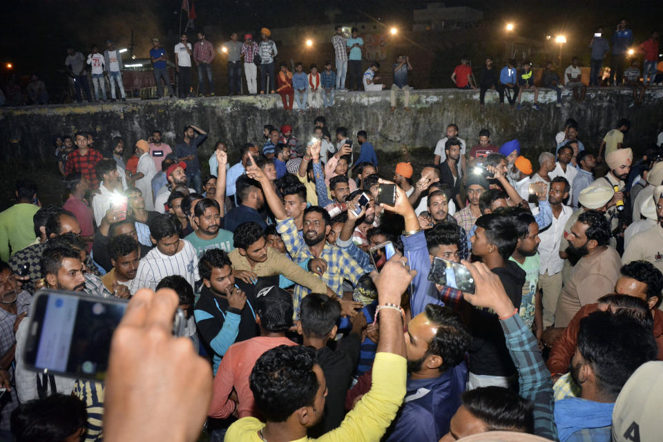 An angry crowd shouts slogans at the site of a train accident in Amritsar, India, Friday, Oct. 19, 2018. A speeding train ran over a crowd watching fireworks during a religious festival in northern India on Friday, killing at least 50 people, a Congress party leader said. (AP Photo/Prabhjot Gill)