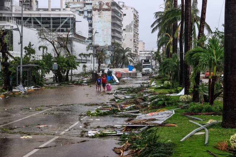A couple walks down a street filled with storm debris in Acapulco, Mexico, on Thursday. Photo by David Guzman/EPA-EFE