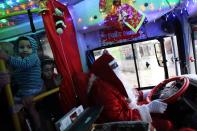Bus driver Edilson, 45, also known as "Fumassa", drives while wearing a Santa Claus outfit inside an urban bus decorated with Christmas motives in Santo Andre, outskirts of Sao Paulo December 10, 2013. Fumassa dresses as Santa Claus every year while driving his bus. Picture taken December 10. REUTERS/Nacho Doce (BRAZIL - Tags: SOCIETY TRANSPORT)