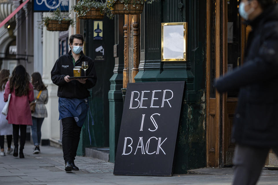 LONDON, ENGLAND - APRIL 16: A waiter at a pub carries a tray of drinks to a table on April 16, 2021 in London, England. Pubs and Restaurants are expecting good business tonight being the first Friday night after Coronavirus lockdown rules were relaxed to allow outside dining and drinking. (Photo by Rob Pinney/Getty Images)