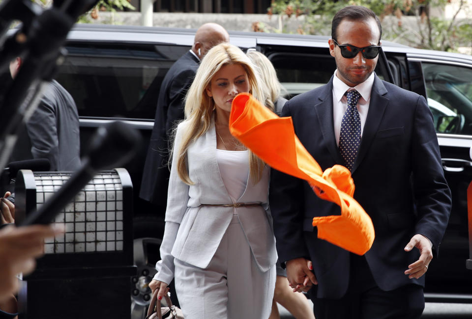 An orange shirt saying "inmate" is thrown by a protester at former Donald Trump presidential campaign foreign policy adviser George Papadopoulos, right, who triggered the Russia investigation, and who pleaded guilty to one count of making false statements to the FBI, as he holds hands with his wife Simona Mangiante on arrival at federal court for sentencing, Friday, Sept. 7, 2018, in Washington. (AP Photo/Jacquelyn Martin)