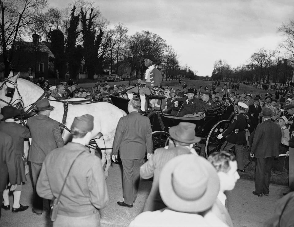 Colonial Williamsburg coachman Benjamin Spraggins sits atop a carriage holding former British Prime Minister Winston Churchill and then-Gen. Dwight D. Eisenhower in Williamsburg, Va., on March 8, 1946. The living history museum is honoring Spraggins, a Black man who worked at the museum during the era of segregation, by naming a new carriage after him. The tribute is part of the museum’s ongoing reckoning over race and its past storytelling about the country’s origins and the role of Black Americans. (AP Photo/William J. Smith)