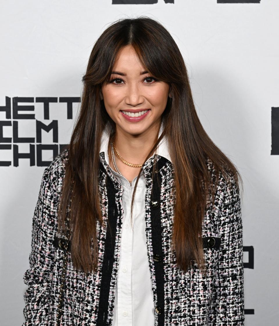 Brenda Song poses in a tweed jacket over a white blouse at the Ghetto Film School event backdrop