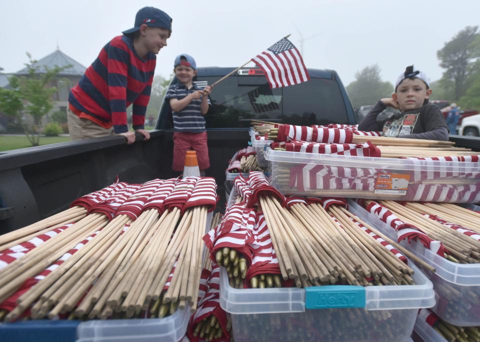 In May, brothers Logan, 9, Hunter, 5, and Bryson Reed, 7, of Sandwich, keep an eye on a truck load of flags as the prepare to head out at the National Cemetery in Bourne where hundreds of volunteers gathered to place tens of thousands of flags on all the veterans' grave in honor of Memorial Day.