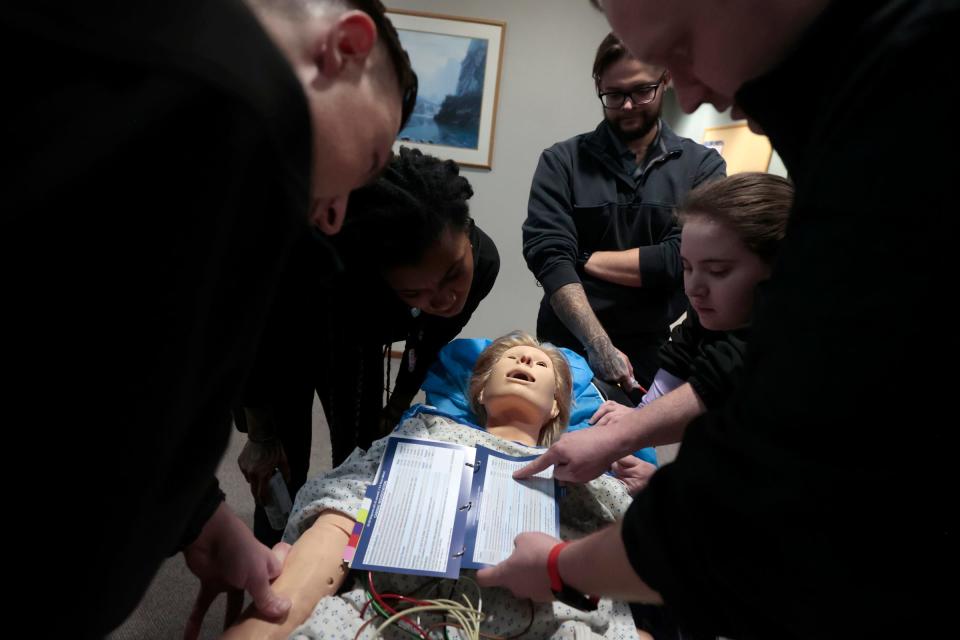 Paramedic students Ryan Rivard, left, Autumn Anderson, Stephen Henderson and Ally Suida listen to Travis Sparling, a paramedic, as he shows them charts on how to determine how much medicine to inject into this mannequin during a training scenario at the Medstar offices in Clinton Township on Wednesday, Nov. 1, 2023. Sparling, a paramedic, was putting the other four through a test to see if they knew the steps to take when presented with a patient who in this scenario was at home complaining of lightheadedness.