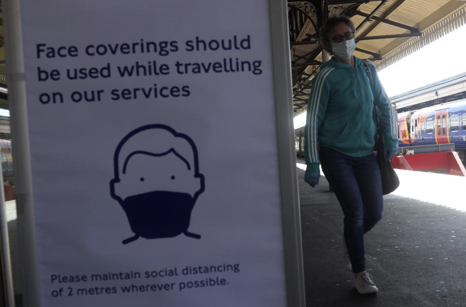 A sign advising passengers to wear a face mask at Clapham Junction station as train services increased as part of the easing of coronavirus lockdown restrictions, in London, Monday May 18, 2020.Britain's Prime Minister Boris Johnson announced last Sunday that people could return to work if they could not work from home. (Yui Mok/PA via AP)