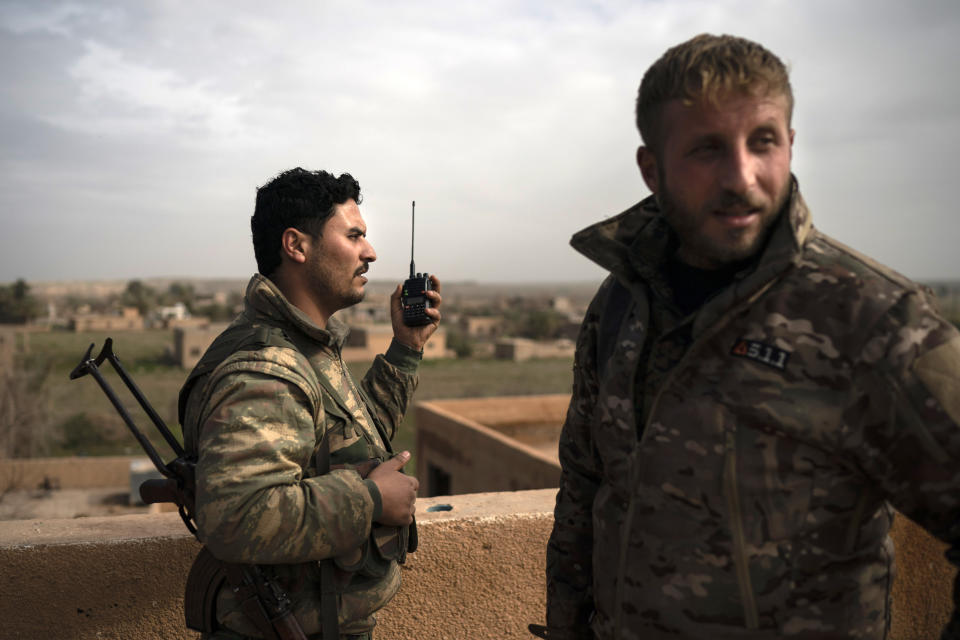 U.S.-backed Syrian Democratic Forces (SDF) fighters talk on a radio in a rooftop position as fight against Islamic State militants continues in the village of Baghouz, Syria, Saturday, Feb. 16, 2019. (AP Photo/Felipe Dana)