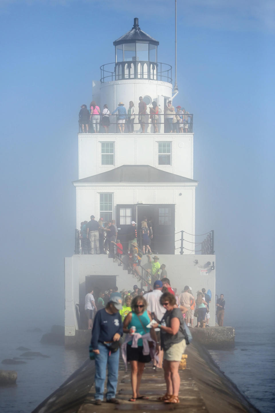 FILE - Fog envelops the lighthouse as people line up along the breakwater wall to get a close look at the new renovations during Subfest July 14, 2018, in Manitowoc.