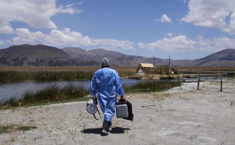 A healthcare worker carries a cooler filled with doses of the Pfizer COVID-19 vaccine during a door-to-door vaccination campaign aimed at Lake Titicaca residents in Puno, Peru, Wednesday, Oct. 27, 2021. While more than 55% of Peruvians have gotten at least one shot of COVID-19 vaccines, only about 25% of people in Indigenous areas have been vaccinated. (AP Photo/Martin Mejia)