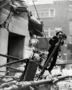 A policeman checks for gas leaking from this street lamp following a daylight raid In October 1940.