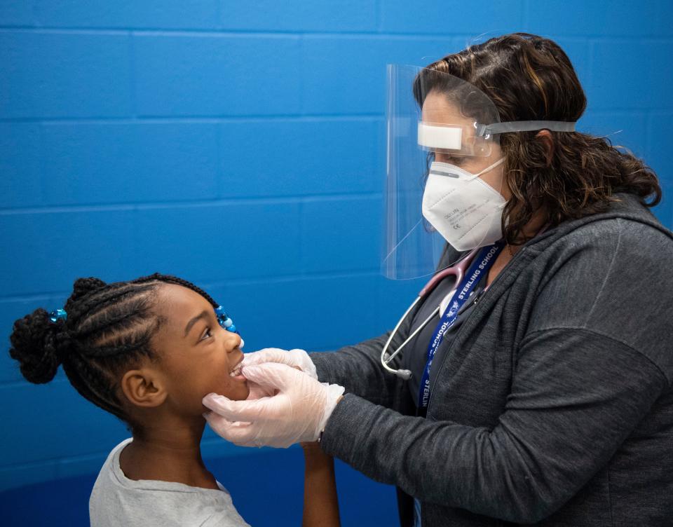 Heather Garrison, a school nurse, inspects the tooth of McKenzie Sutton-Martin, 7, after she said it was causing her pain inside the nurses office at Sterling School, in Greenville, Wednesday, October 20, 2021. 