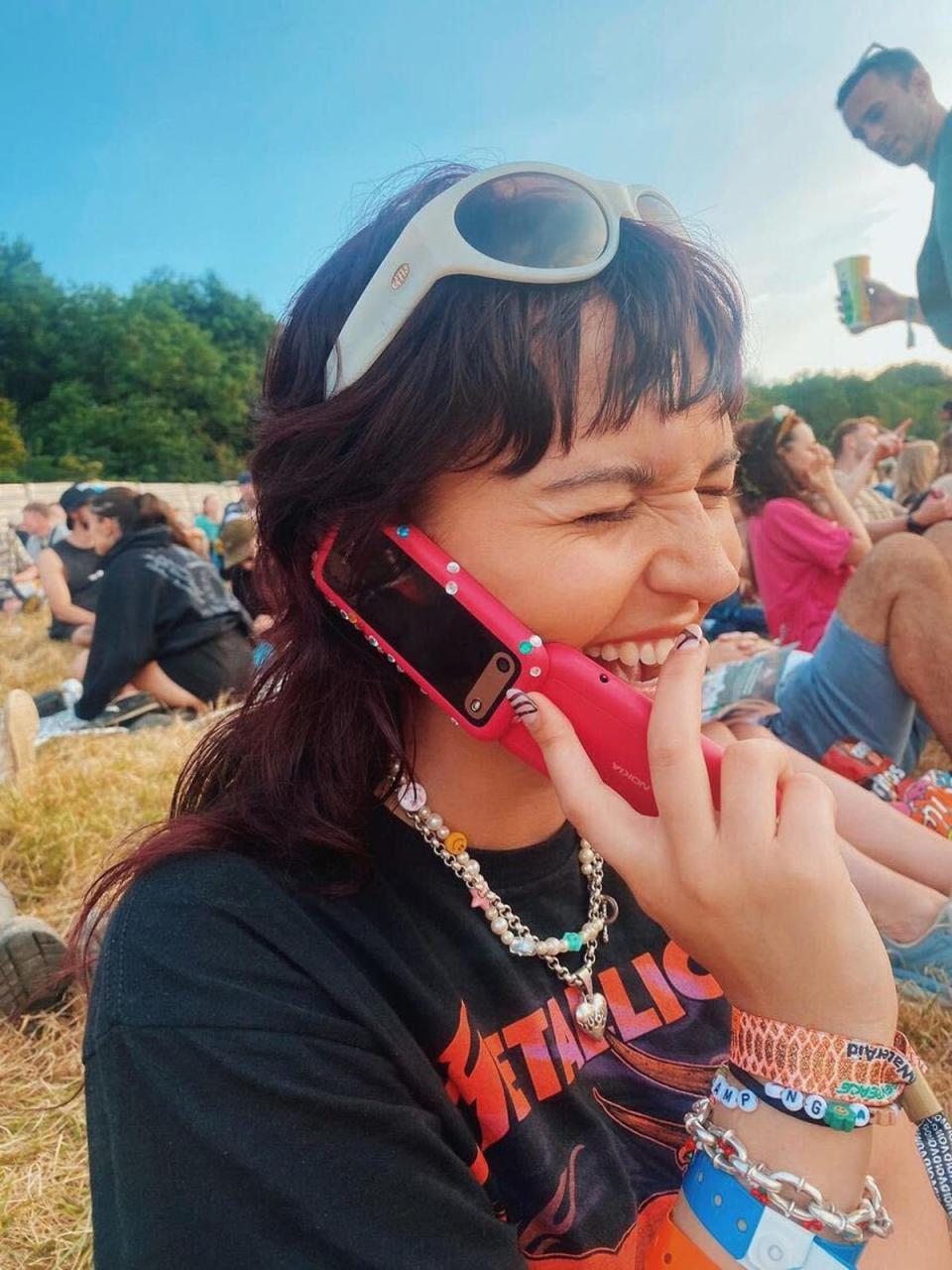 Sophie using her flip phone at Glastonbury 2023 (ES)