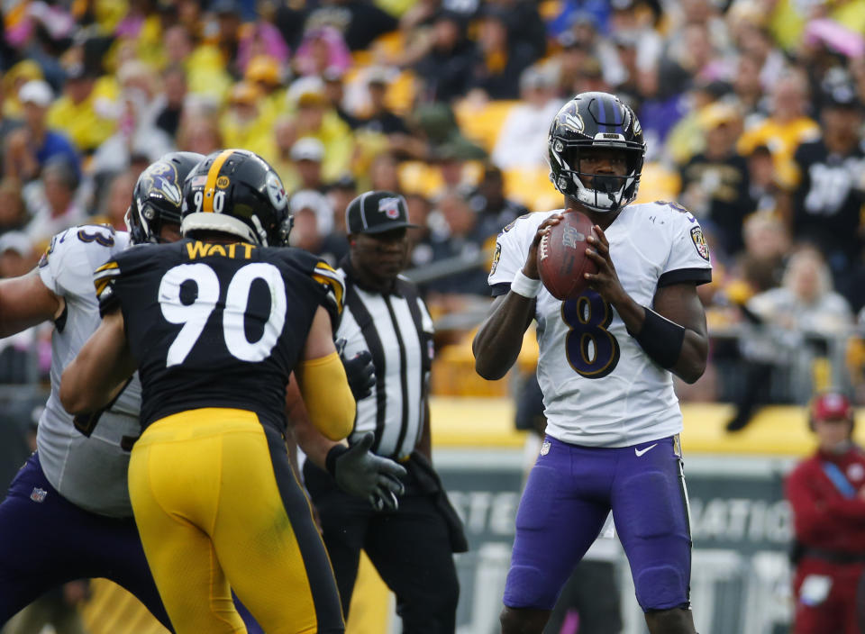 Lamar Jackson holds onto the ball before a throw as T.J. Watt makes a move toward the quarterback.