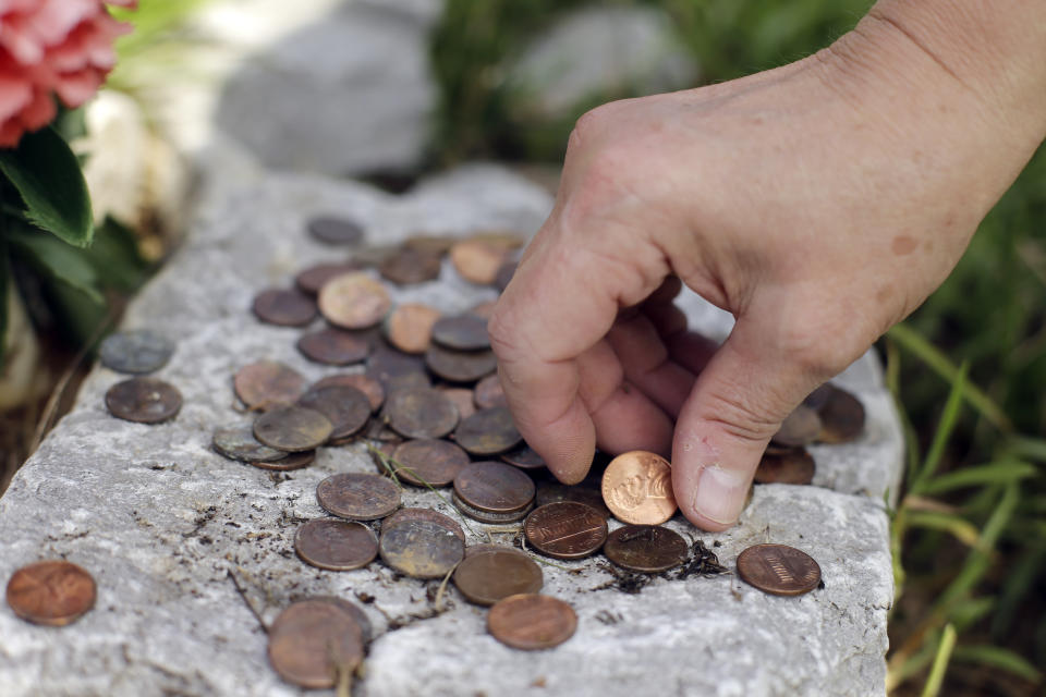 FILE - Janie Clark places pennies at a memorial her husband, Ansol Clark, constructed near the Kingston Fossil Plant on Aug. 6, 2029, in Kingston, Tenn. Attorneys for a group of workers who believe their jobs cleaning up a massive coal ash spill in Tennessee led to a slew of illnesses, including fatal cancers, have reached a settlement with the contractor who organized the cleanup for the Tennessee Valley Authority, according to a notice posted on the Jacobs Engineering website on Tuesday, May 23, 2023. (AP Photo/Mark Humphrey, File)