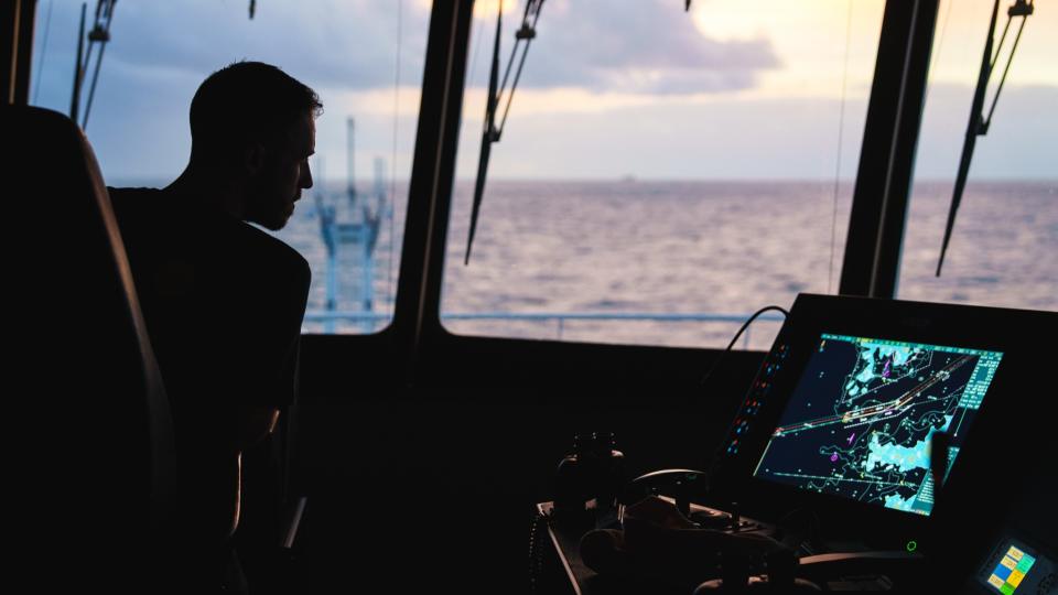 The chief officer of the expedition stands in the control room looking at a digital maritime map.